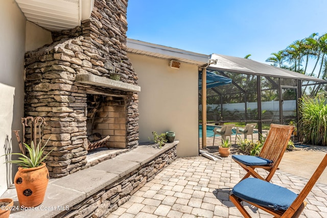 view of patio / terrace with a fenced in pool, glass enclosure, and an outdoor stone fireplace