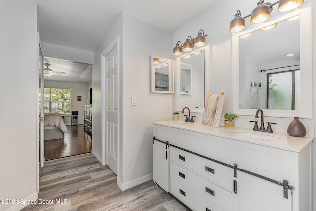 bathroom with vanity, hardwood / wood-style floors, a textured ceiling, and ceiling fan