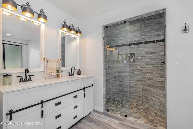 bathroom with vanity, hardwood / wood-style floors, a tile shower, and a textured ceiling