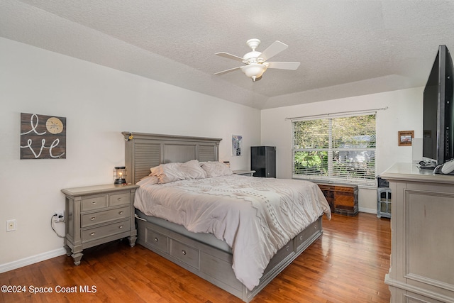 bedroom with a textured ceiling, wood-type flooring, and ceiling fan