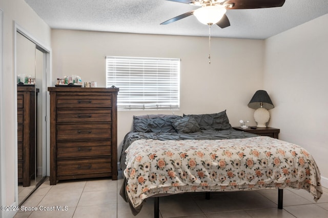 bedroom featuring a textured ceiling, light tile patterned floors, and ceiling fan