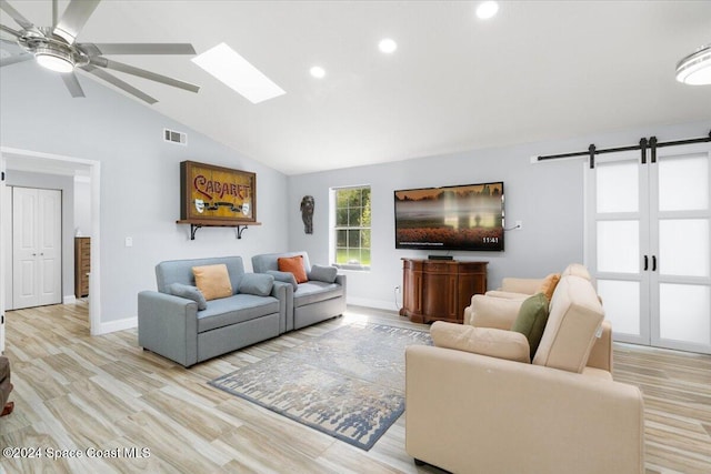 living room featuring a barn door, high vaulted ceiling, light wood-type flooring, and ceiling fan