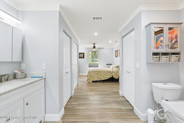 bathroom featuring hardwood / wood-style floors, ceiling fan, toilet, ornamental molding, and vanity