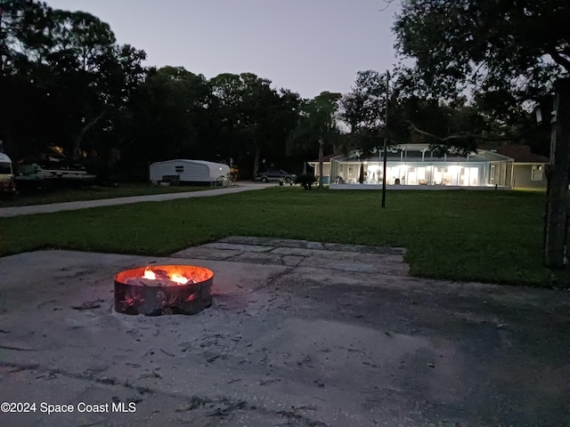 exterior space with an outdoor fire pit and a lawn