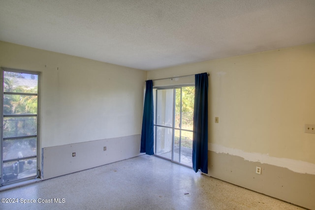 unfurnished room with a textured ceiling and a healthy amount of sunlight