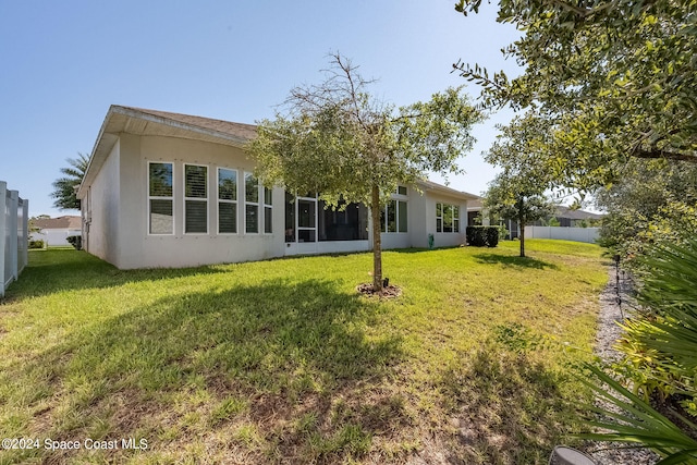 rear view of property with a sunroom and a lawn