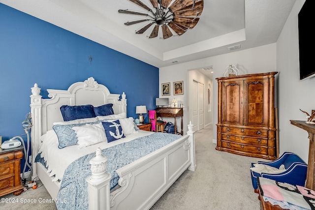 bedroom featuring ceiling fan, a closet, a raised ceiling, and light colored carpet