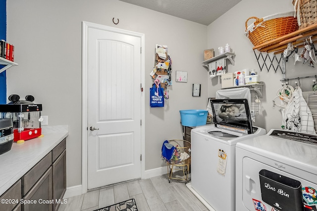 laundry room with light hardwood / wood-style flooring, washing machine and dryer, cabinets, and a textured ceiling