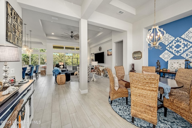 dining area featuring a raised ceiling, ceiling fan with notable chandelier, and light hardwood / wood-style floors