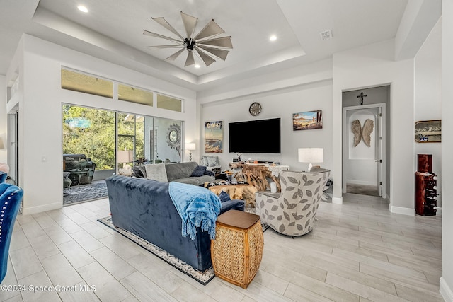 living room featuring a tray ceiling and light hardwood / wood-style flooring