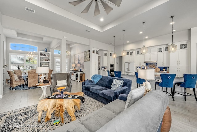 living room with a raised ceiling and light hardwood / wood-style floors