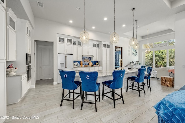 kitchen featuring a large island, hanging light fixtures, and white cabinetry