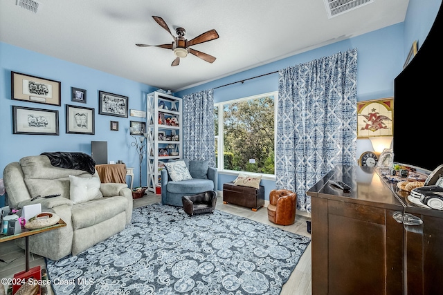 living area with wood-type flooring and ceiling fan