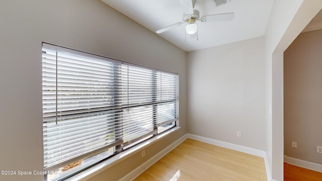 spare room with ceiling fan, a wealth of natural light, and light wood-type flooring