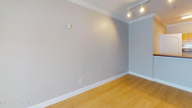 empty room with crown molding, hardwood / wood-style flooring, and rail lighting