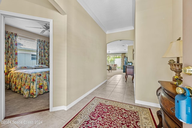 hallway featuring ornamental molding, light tile patterned floors, and a textured ceiling