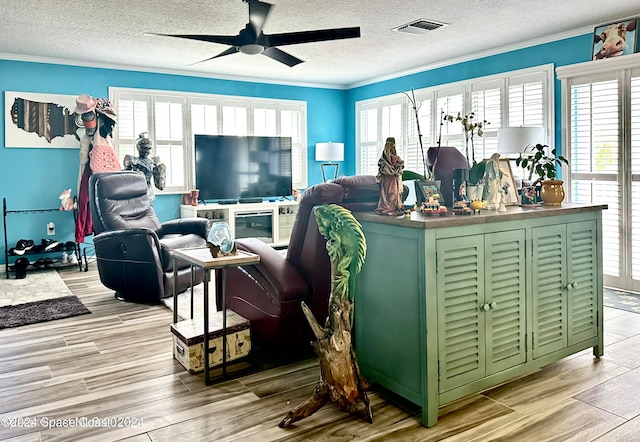 living room with ceiling fan, a textured ceiling, light hardwood / wood-style flooring, and ornamental molding