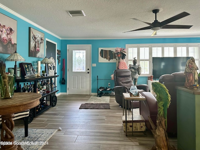 living area featuring ceiling fan, crown molding, hardwood / wood-style flooring, and a textured ceiling