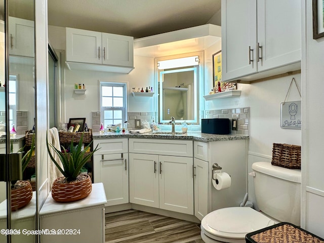 bathroom featuring decorative backsplash, hardwood / wood-style floors, vanity, and toilet