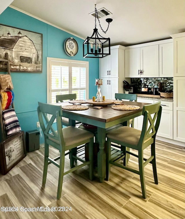 dining space with ornamental molding, a chandelier, and light hardwood / wood-style flooring