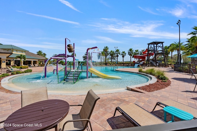 view of swimming pool featuring a patio, a water slide, and a playground