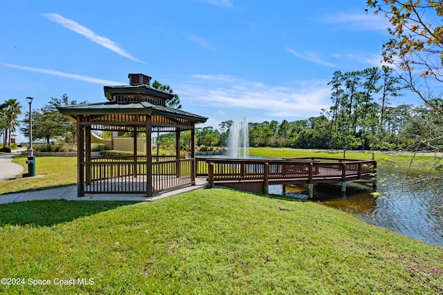 dock area with a water view, a gazebo, and a yard