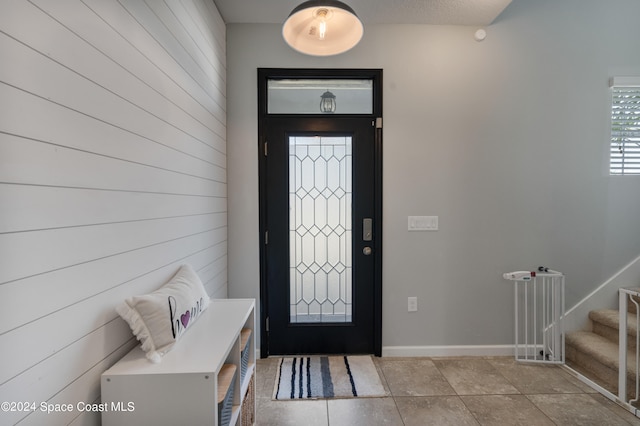 entrance foyer featuring wood walls and light tile patterned floors