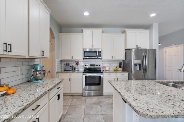 kitchen featuring white cabinetry, light stone counters, appliances with stainless steel finishes, and sink