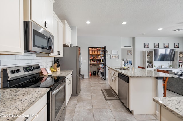 kitchen featuring light stone countertops, a kitchen bar, stainless steel appliances, and white cabinets