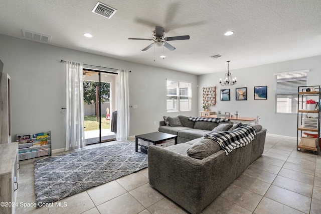 tiled living room with a textured ceiling and ceiling fan with notable chandelier