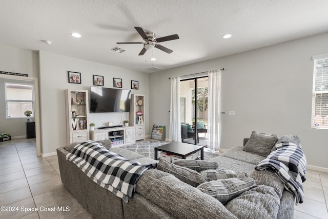 tiled living room featuring ceiling fan, a healthy amount of sunlight, and a textured ceiling