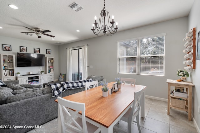 tiled dining area featuring a textured ceiling and ceiling fan with notable chandelier