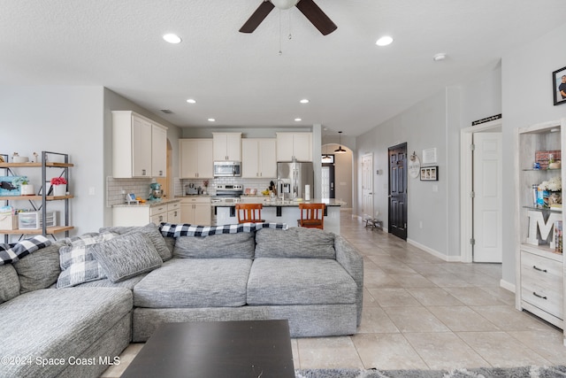 living room featuring light tile patterned flooring, a textured ceiling, and ceiling fan