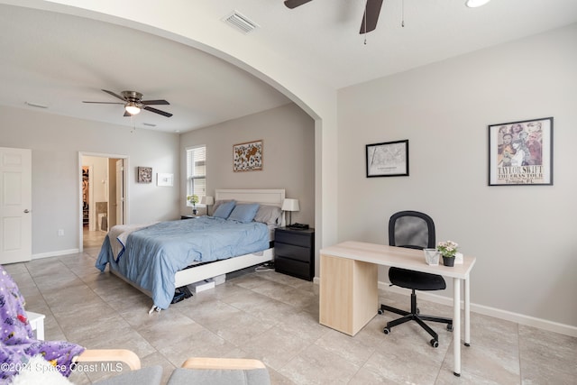 bedroom featuring connected bathroom, light tile patterned floors, and ceiling fan