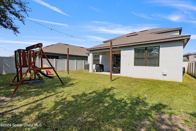 rear view of house featuring a patio, a lawn, and a playground