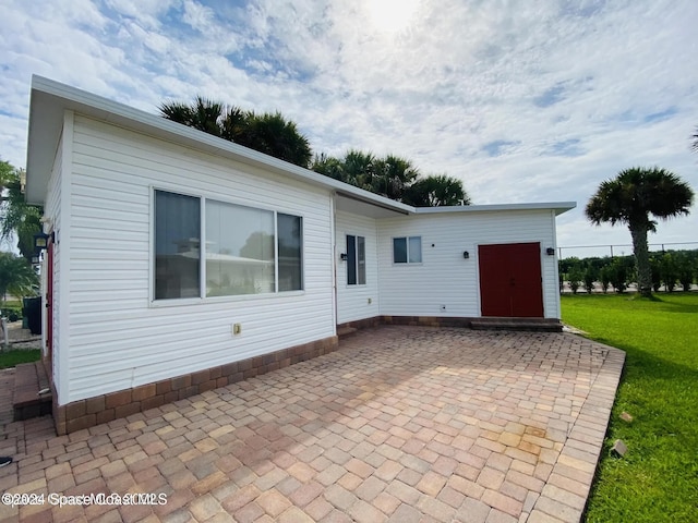 rear view of house featuring a lawn and a patio