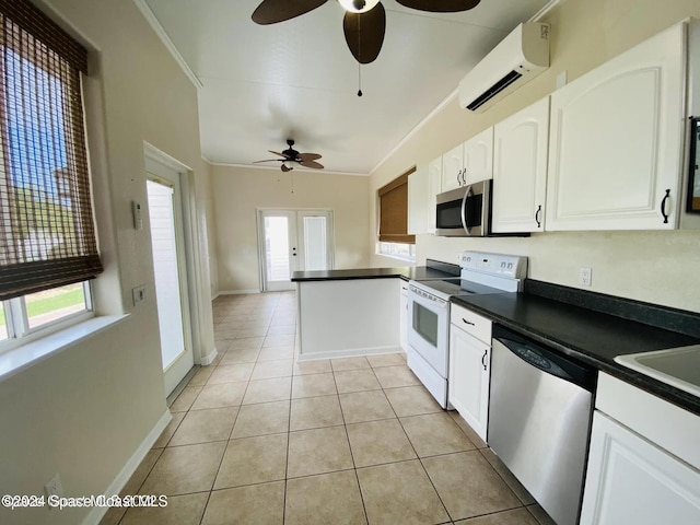 kitchen featuring light tile patterned floors, a wall unit AC, stainless steel appliances, and white cabinets