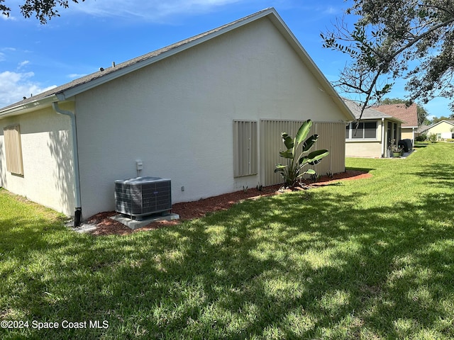 rear view of house with central AC unit and a yard