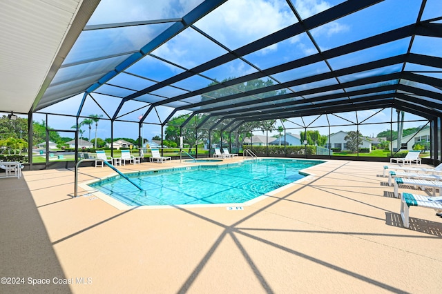 view of swimming pool featuring glass enclosure and a patio