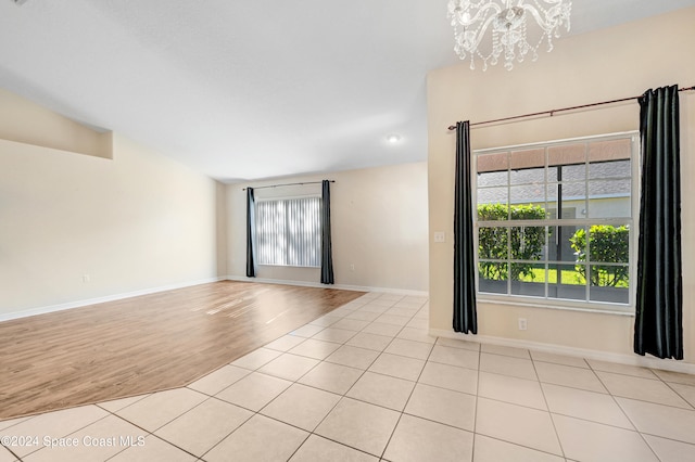 unfurnished room featuring a chandelier and light hardwood / wood-style flooring