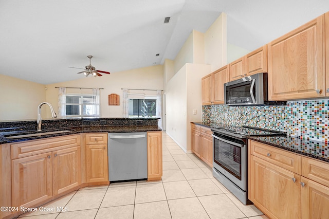 kitchen featuring stainless steel appliances, vaulted ceiling, dark stone countertops, and sink