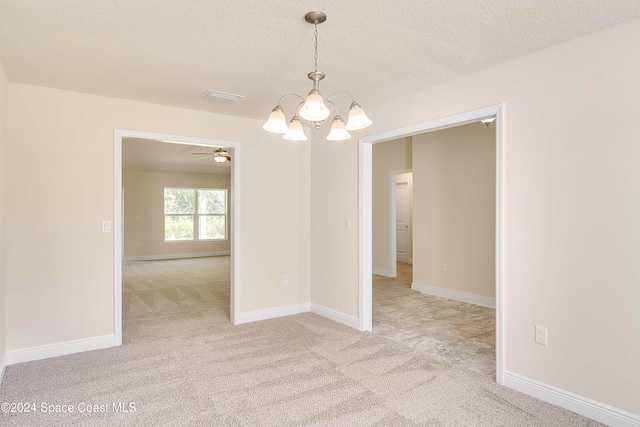 spare room featuring ceiling fan with notable chandelier, a textured ceiling, and light carpet