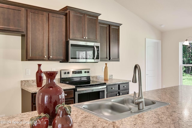 kitchen with stainless steel appliances, dark brown cabinetry, lofted ceiling, and sink