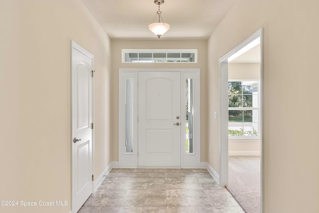 entryway with light colored carpet and a textured ceiling