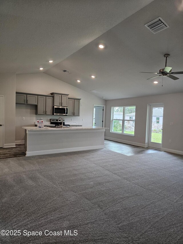 713 Degroodt Rd SW, Palm Bay, FL 32908 - kitchen with stainless steel microwave, gray cabinets, baseboards, dark carpet, and lofted ceiling