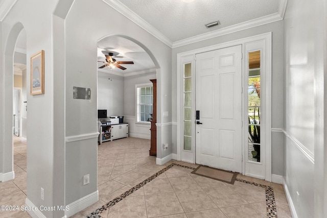 tiled foyer entrance featuring ornamental molding, a textured ceiling, and ceiling fan