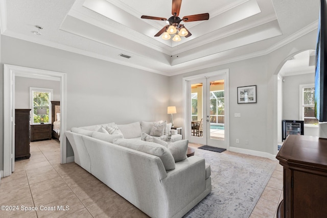 tiled living room featuring crown molding, a healthy amount of sunlight, a tray ceiling, and ceiling fan