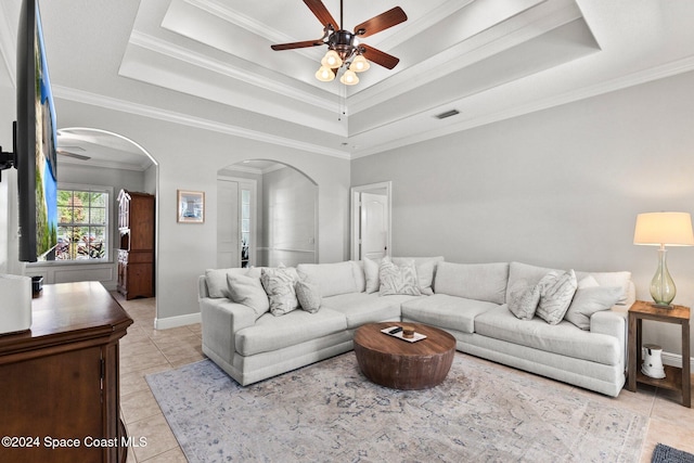 tiled living room with crown molding, a tray ceiling, and ceiling fan