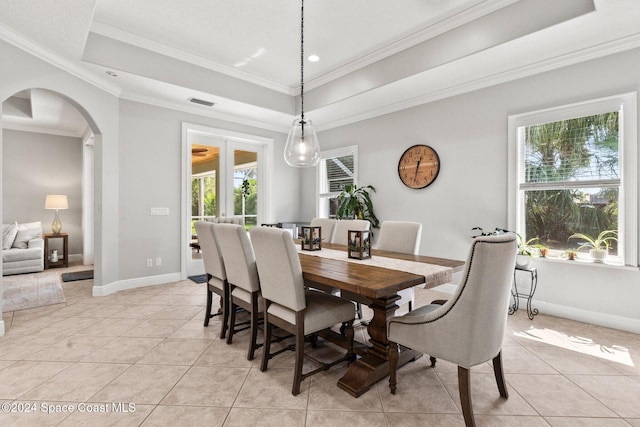 dining room featuring crown molding, a raised ceiling, and light tile patterned floors