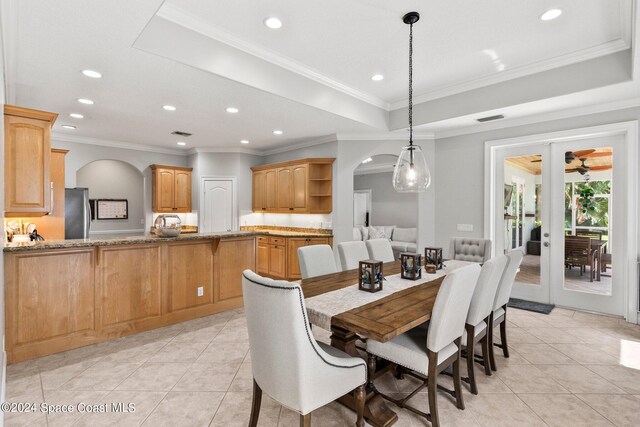 tiled dining space featuring crown molding, french doors, a tray ceiling, and ceiling fan